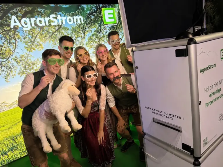 Gäste mit Fotoaccessoires vor einer Fotobox bei einer Veranstaltung in der Steiermark